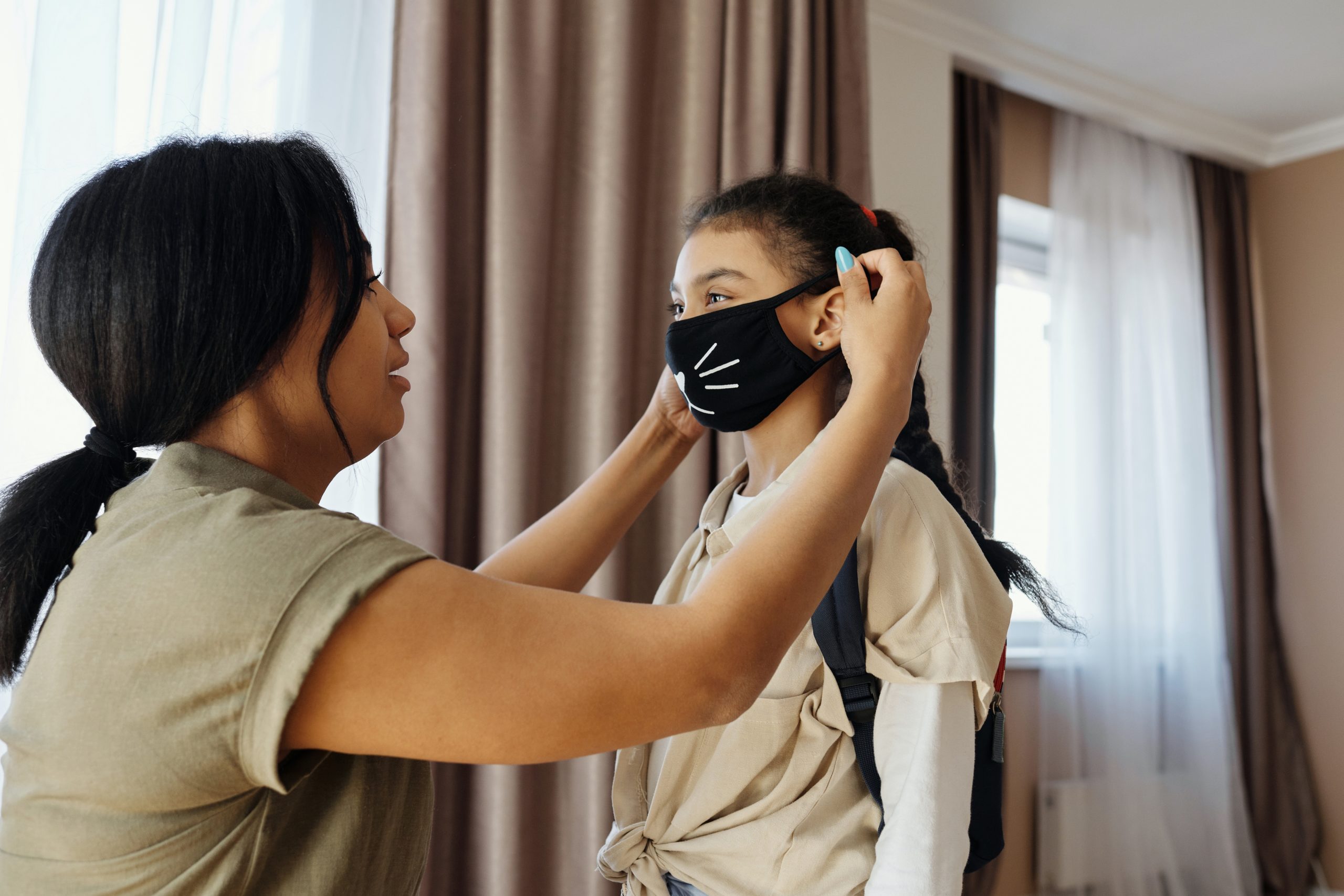 Mother putting COVID-19 mask on child